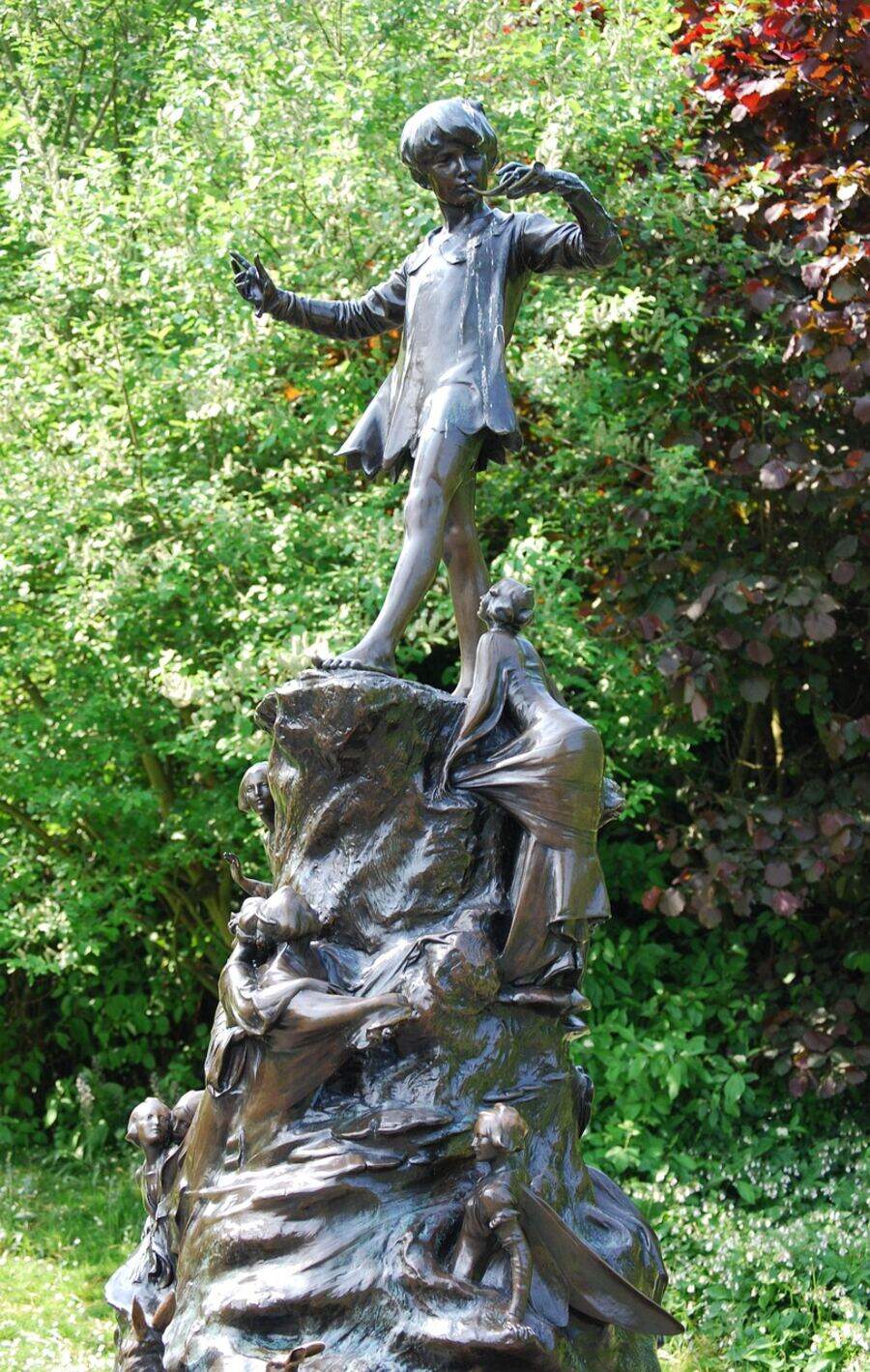 The Peter Pan statue in Kensington Gardens. A bronze boy standing atop a tree stump covered in fairies, rabbits, and mice.