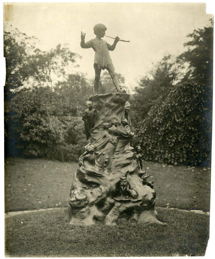 The Peter Pan statue in Kensington Gardens, circa 1920s. A bronze boy on a tree stump, horn raised, frozen mid-note.